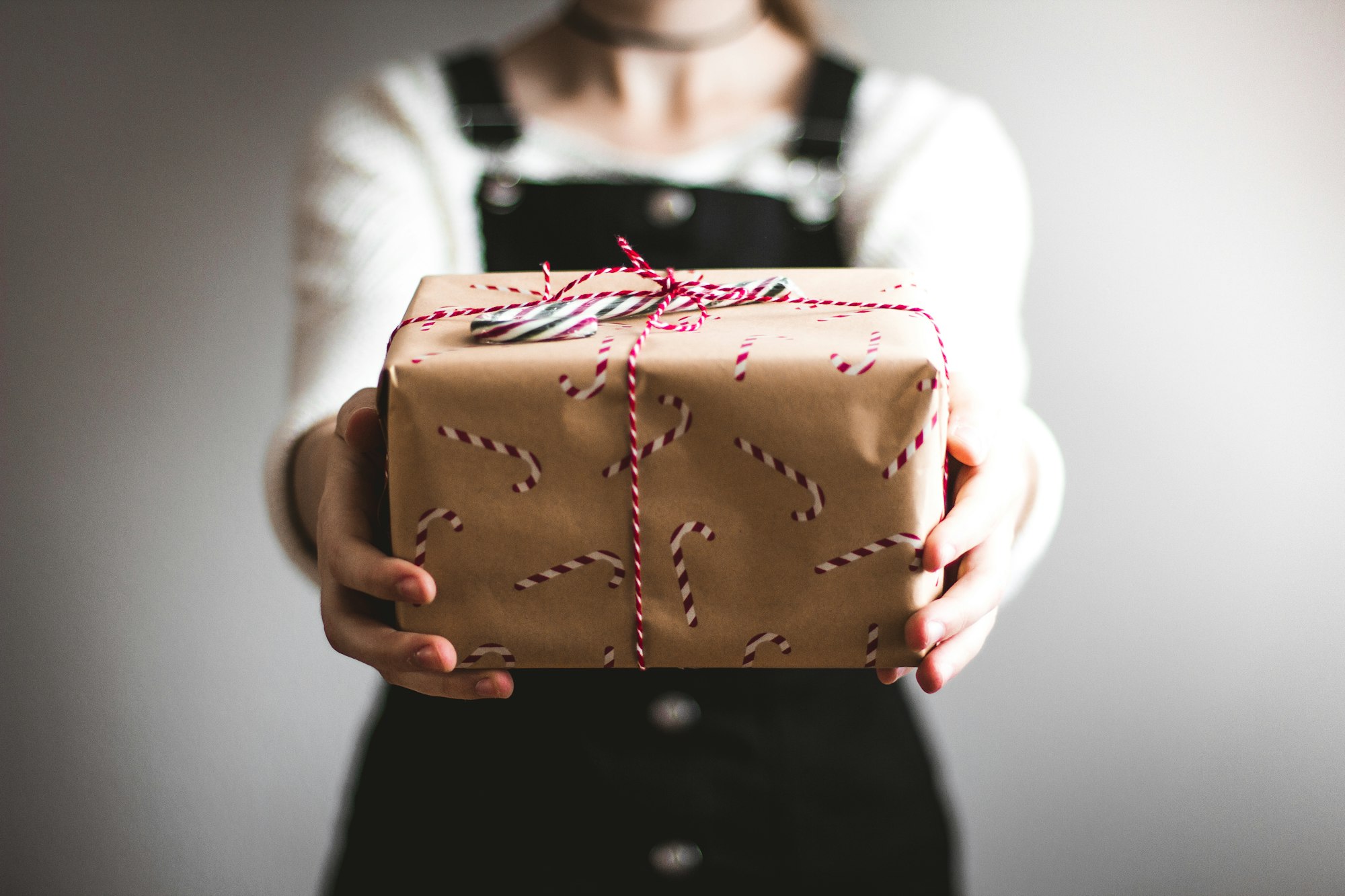 Persona entregando un regalo envuelto en papel kraft con listón