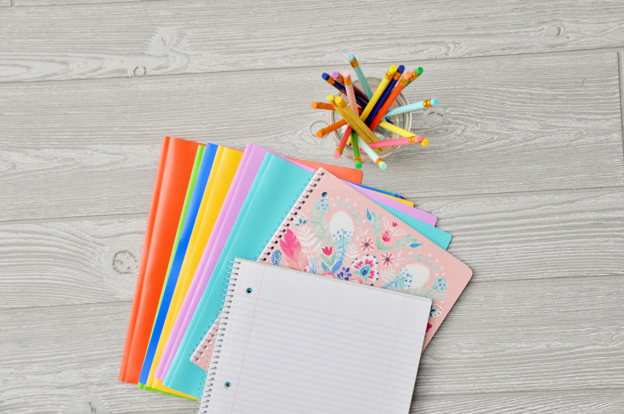Pila de cuadernos de colores apilados sobre una mesa de madera